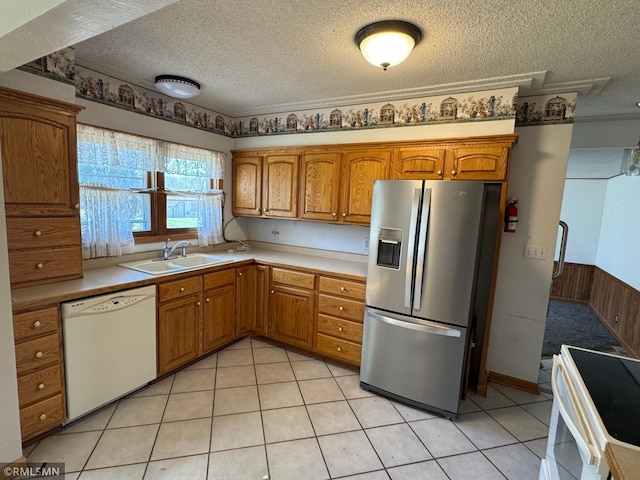 kitchen featuring a sink, brown cabinets, white appliances, light countertops, and a textured ceiling