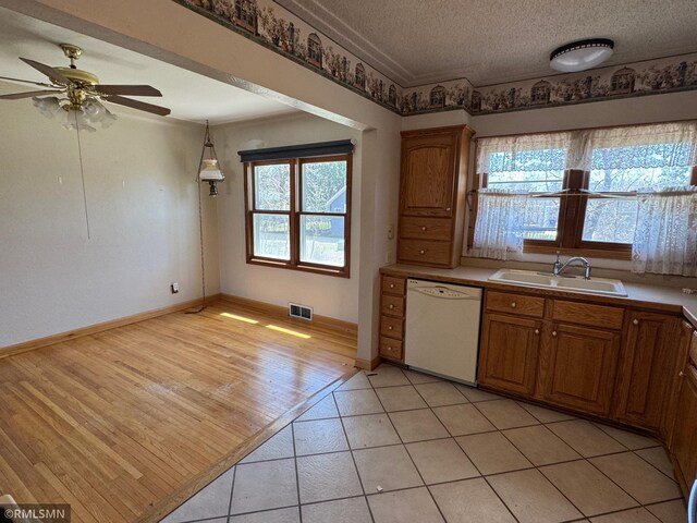 kitchen featuring a sink, white dishwasher, brown cabinets, and visible vents