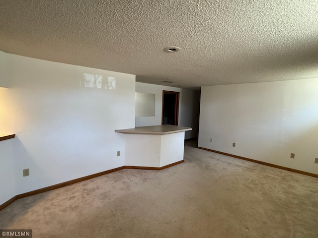 spare room featuring baseboards, light carpet, and a textured ceiling