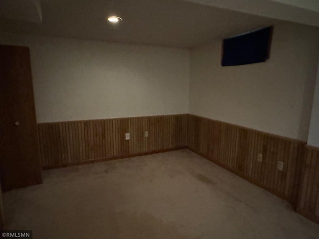finished below grade area featuring light colored carpet, recessed lighting, and wainscoting