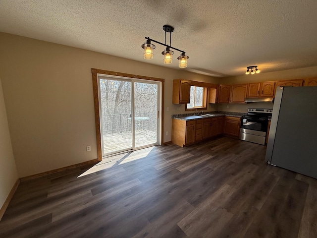 kitchen with dark countertops, a textured ceiling, appliances with stainless steel finishes, and under cabinet range hood