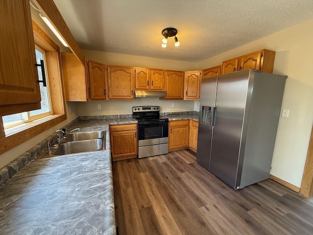 kitchen with dark wood-style floors, a sink, stainless steel appliances, and under cabinet range hood