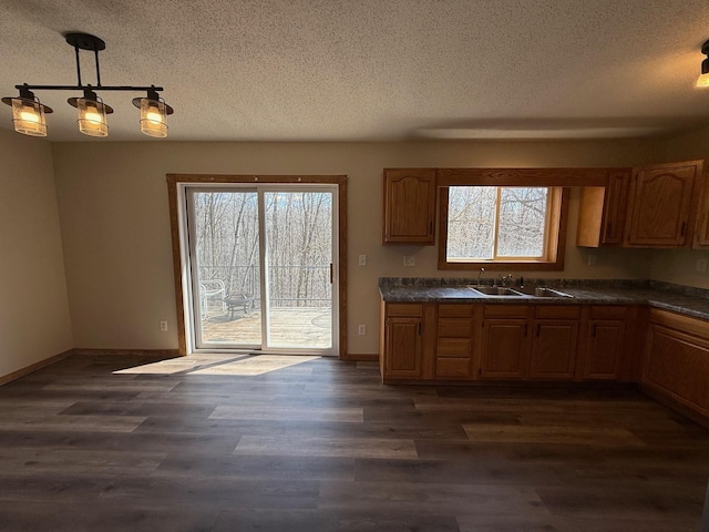 kitchen with dark countertops, a textured ceiling, dark wood-type flooring, and a sink