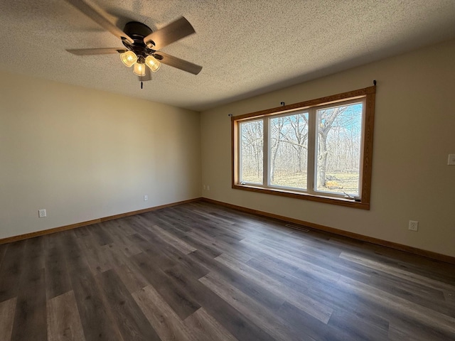 spare room with dark wood-style floors, baseboards, a ceiling fan, and a textured ceiling