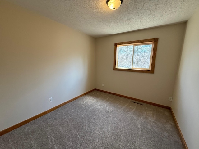 unfurnished room featuring a textured ceiling, visible vents, carpet floors, and baseboards