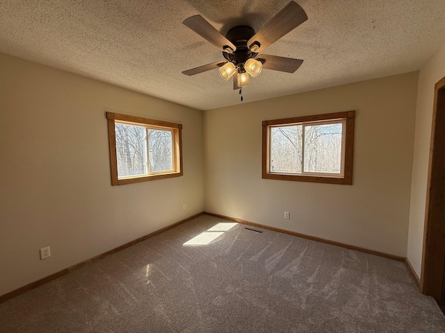 carpeted empty room with baseboards, ceiling fan, a textured ceiling, and plenty of natural light