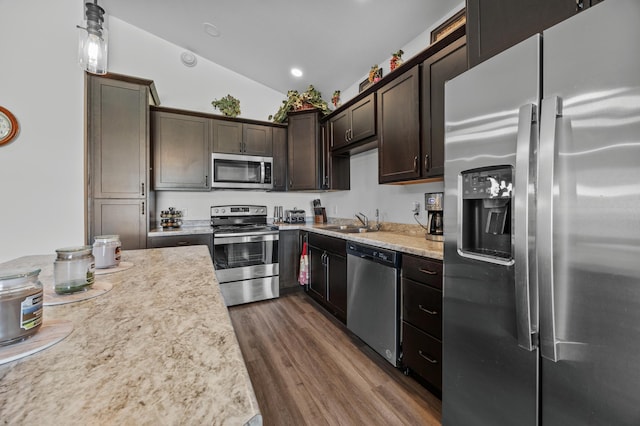 kitchen featuring dark brown cabinetry, dark wood-style flooring, appliances with stainless steel finishes, a sink, and light countertops