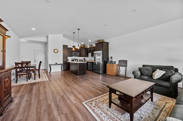 living area with baseboards, light wood-type flooring, and lofted ceiling