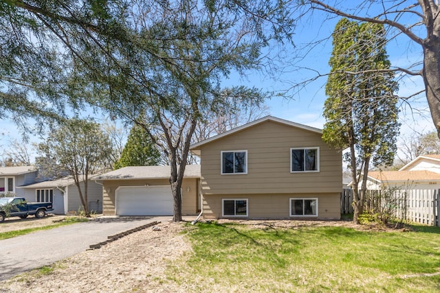 tri-level home with a garage, a front lawn, fence, and driveway