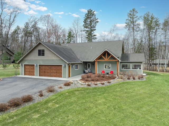 craftsman-style house with a front yard, aphalt driveway, and roof with shingles