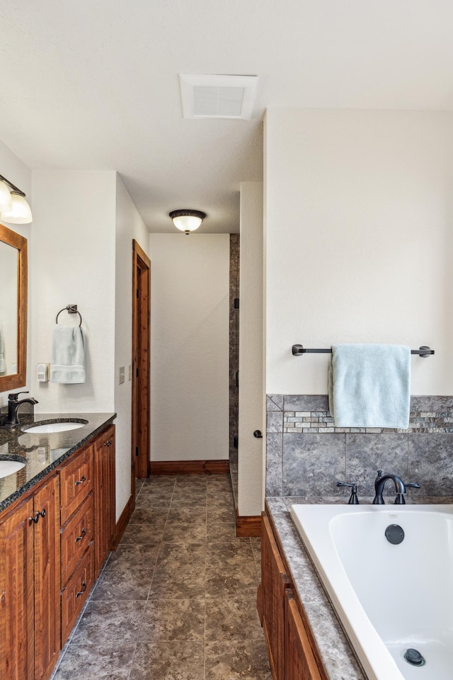 full bathroom with a sink, double vanity, visible vents, baseboards, and a garden tub
