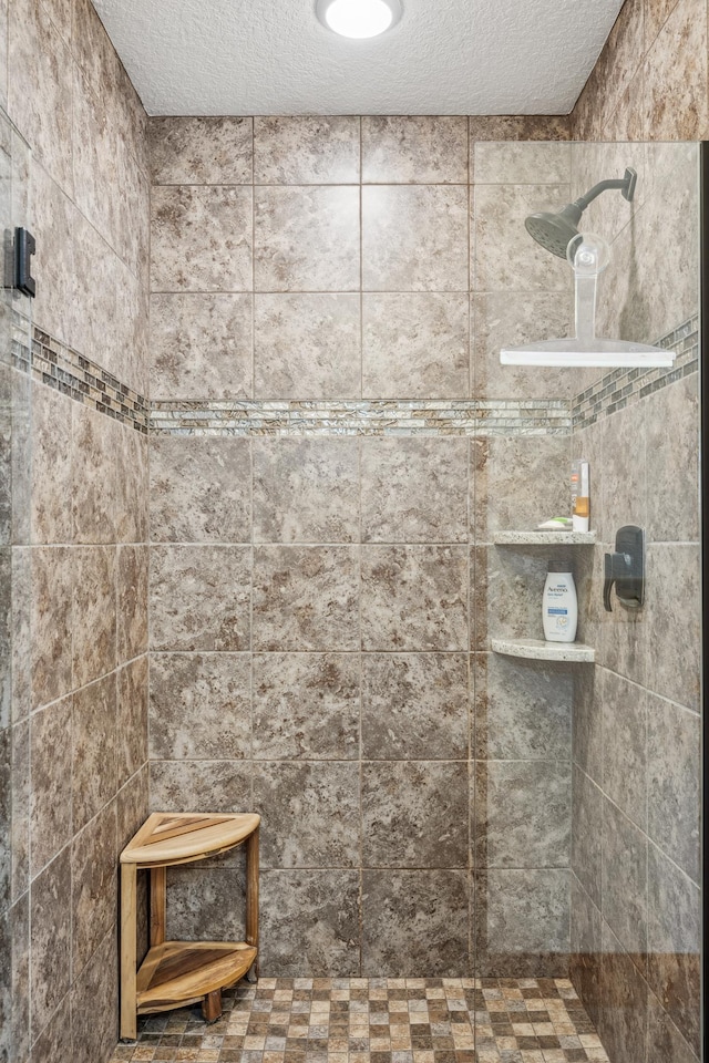 bathroom with tiled shower and a textured ceiling