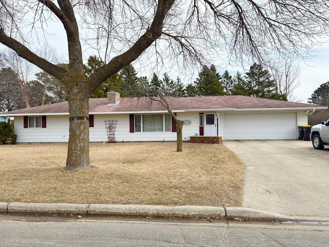 ranch-style home featuring an attached garage, a front lawn, a chimney, and concrete driveway