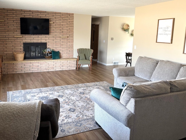 living room with baseboards, visible vents, wood finished floors, and a fireplace