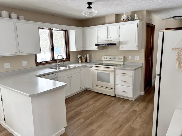 kitchen featuring a sink, under cabinet range hood, white appliances, and white cabinetry
