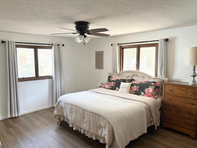 bedroom featuring a textured ceiling, multiple windows, and wood finished floors