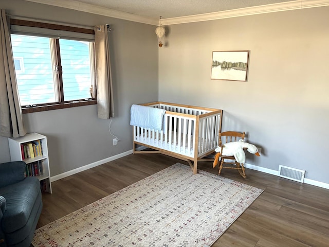 bedroom with baseboards, visible vents, ornamental molding, and wood finished floors