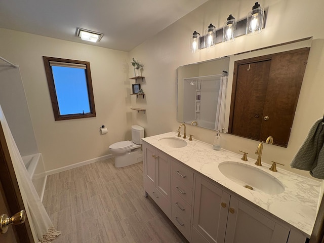 full bath with baseboards, a sink, double vanity, and toilet