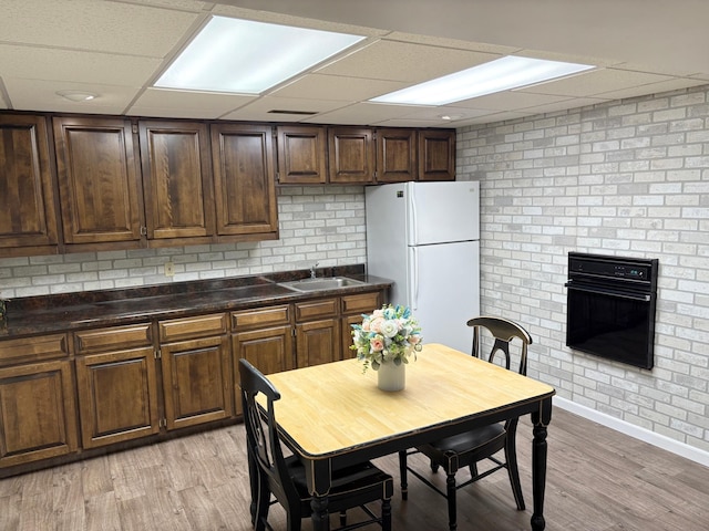 kitchen with a drop ceiling, dark countertops, a sink, freestanding refrigerator, and black oven