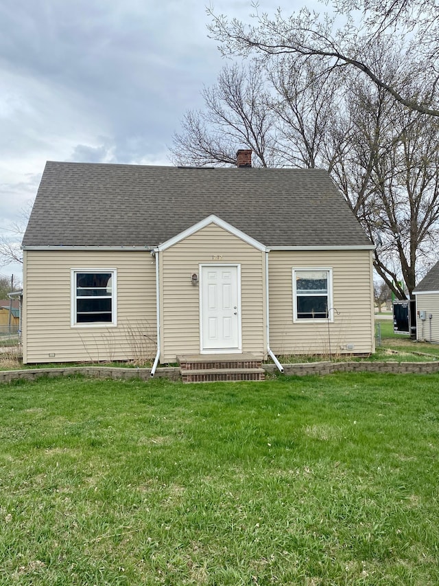 view of front of home featuring a front lawn, roof with shingles, and a chimney