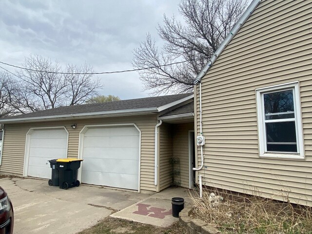view of property exterior with roof with shingles and a garage