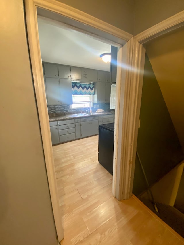 hall with light wood finished floors and a sink