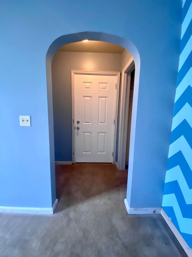 carpeted entrance foyer featuring arched walkways and baseboards