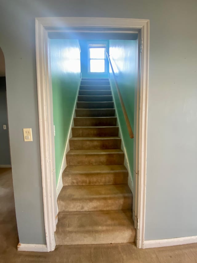 stairway featuring baseboards and arched walkways