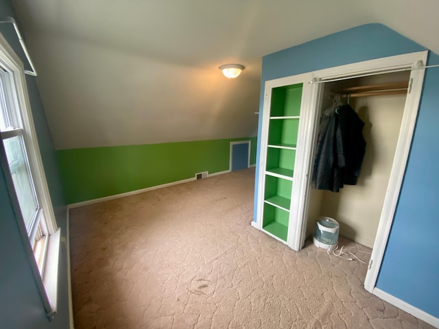 interior space featuring carpet, visible vents, and vaulted ceiling