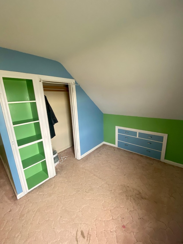 additional living space with baseboards, built in features, and vaulted ceiling