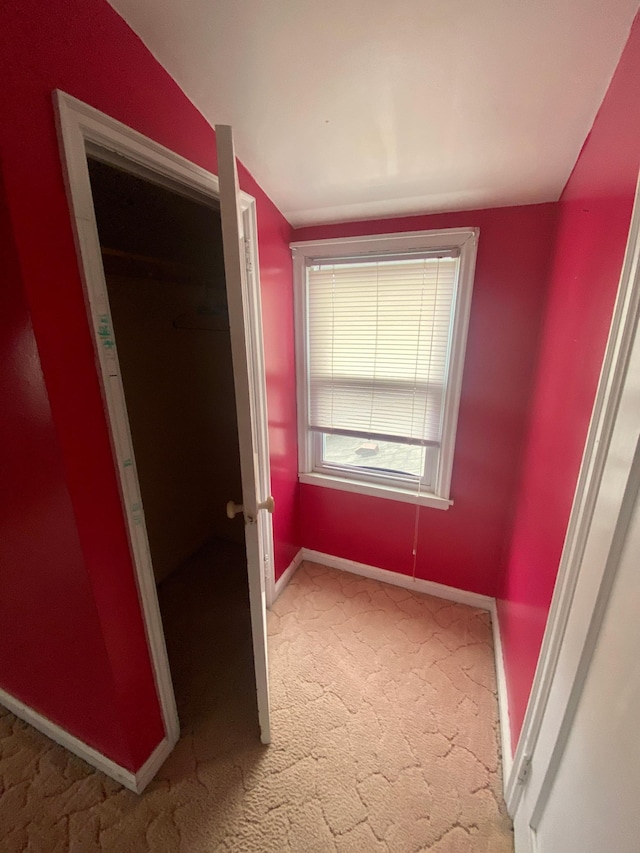 unfurnished bedroom featuring lofted ceiling, carpet, and baseboards