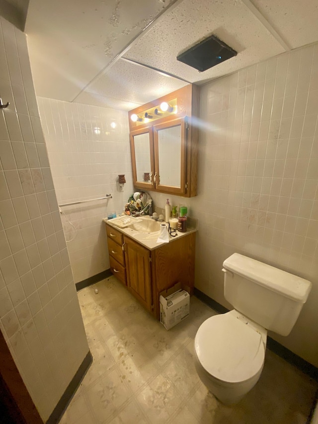 bathroom with tile patterned floors, toilet, vanity, and tile walls