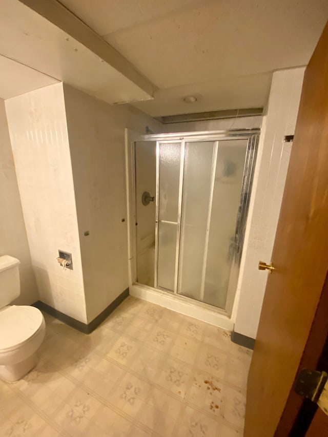 full bathroom featuring tile patterned floors, toilet, a shower stall, and baseboards