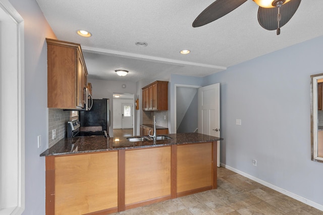 6049 Wentworth Ave, Minneapolis, MN 55419 - kitchen with stainless steel appliances, brown cabinetry, a textured ceiling, tasteful backsplash, and dark stone counters