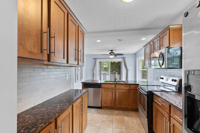 6049 Wentworth Ave, Minneapolis, MN 55419 - kitchen featuring stainless steel appliances, brown cabinets, a textured ceiling, dark stone counters, and backsplash