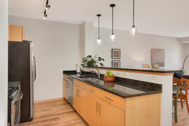 kitchen featuring a peninsula, stainless steel appliances, a sink, light brown cabinets, and light wood finished floors