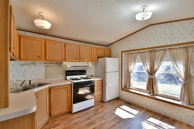 kitchen with a sink, wallpapered walls, white appliances, lofted ceiling, and ornamental molding