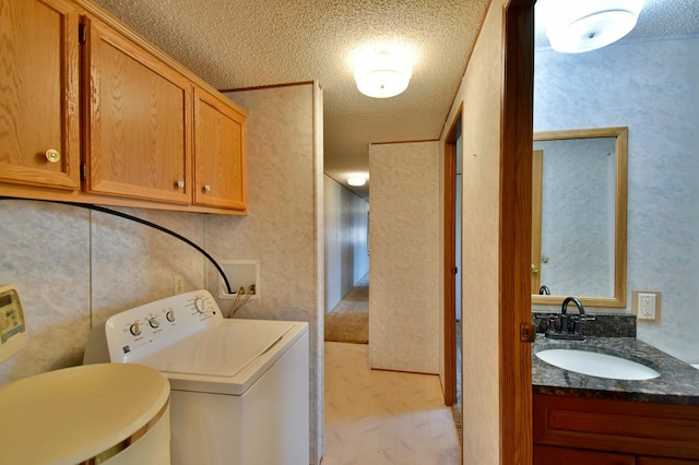 clothes washing area featuring a sink, washer / clothes dryer, a textured ceiling, and laundry area