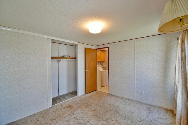 unfurnished bedroom featuring washer / clothes dryer, light carpet, a textured ceiling, and a closet
