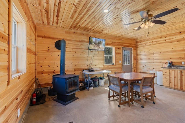 8494 Peary Junction Rd, Kelsey, MN 55724 - dining area featuring a wood stove, finished concrete floors, wooden walls, and ceiling fan