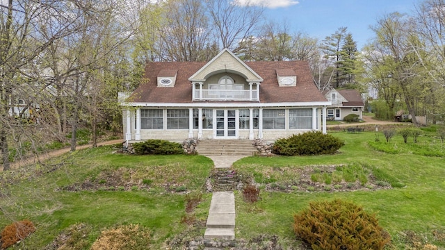 view of front of home featuring a balcony, a sunroom, and a front lawn