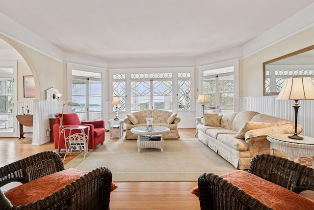 living room with arched walkways, wainscoting, and wood finished floors