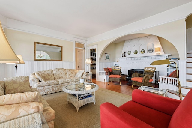 living area with wainscoting, wood finished floors, and a fireplace