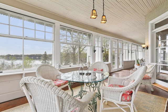 sunroom / solarium with a water view, french doors, wood finished floors, and a wealth of natural light