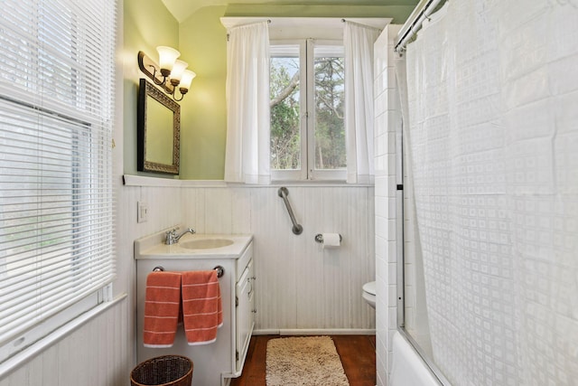 full bathroom with vanity, toilet, a wainscoted wall, combined bath / shower with glass door, and wood finished floors