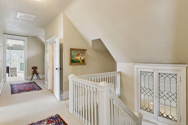 corridor with carpet floors, baseboards, lofted ceiling, and an upstairs landing