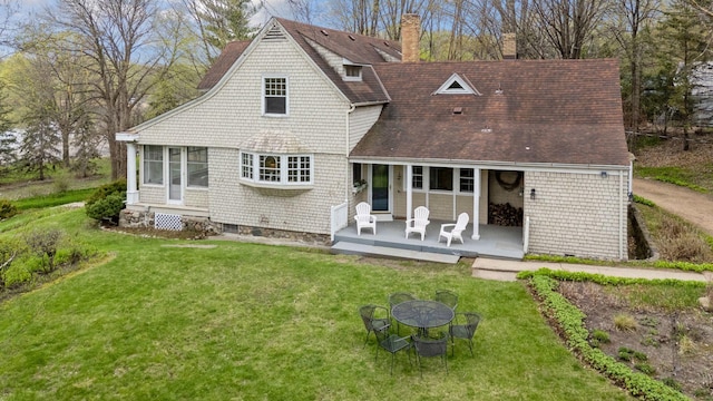 rear view of property featuring a fire pit, roof with shingles, a yard, and a chimney