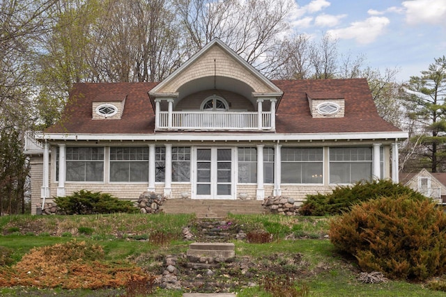 view of front of property with roof with shingles, a sunroom, and a balcony