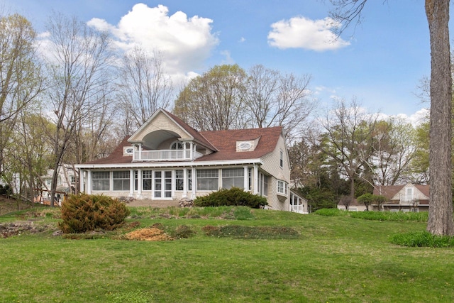 rear view of house with a yard, a sunroom, and a balcony