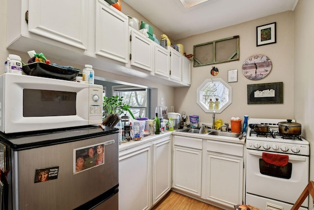 kitchen with a sink, white cabinetry, white appliances, and light countertops